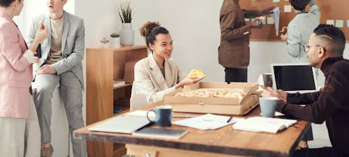Office team enjoying pizza together during a work lunch meeting