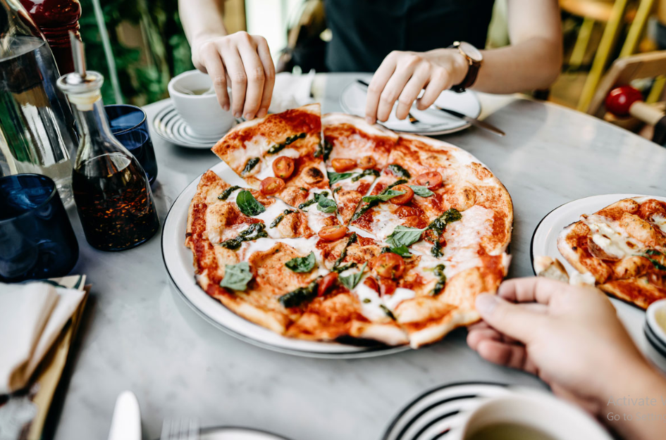 Hands reaching for slices of pizza during a group meal