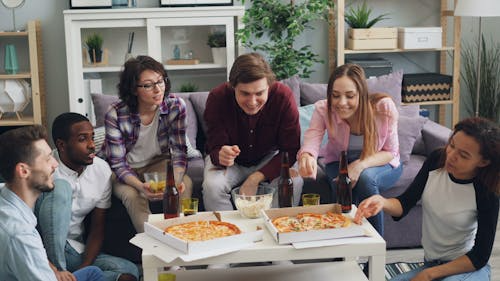 Group of friends sitting around a table enjoying pizza together