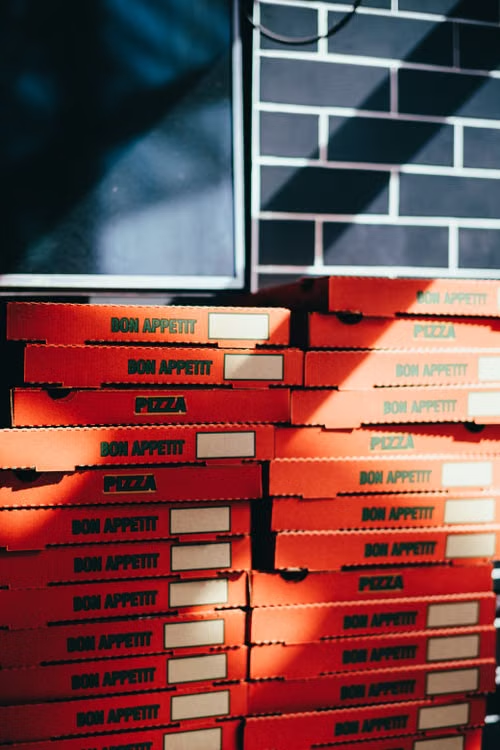 Vertical stack of orange pizza boxes prepared for a corporate catering order