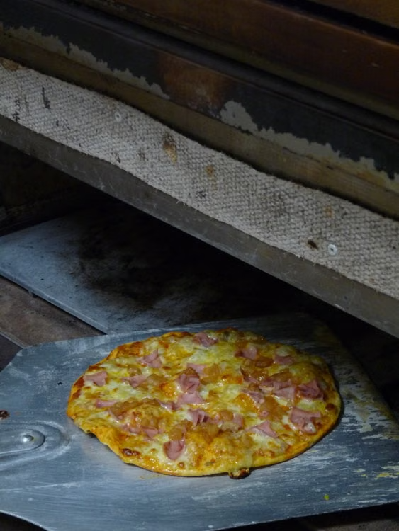 a freshly baked thin crust pizza out of the oven