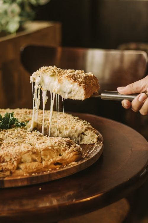 close-up of a person taking a slice of a cheese stuffed pizza