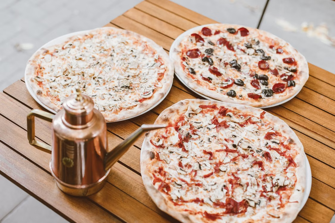 This photo shows a pizza on a brown table.
